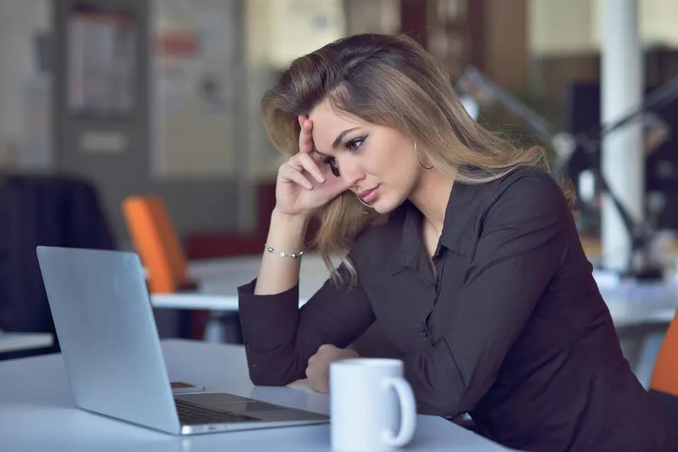 A woman sitting at her desk with a distant expression, symbolizing emotional burnout and lack of career fulfillment.